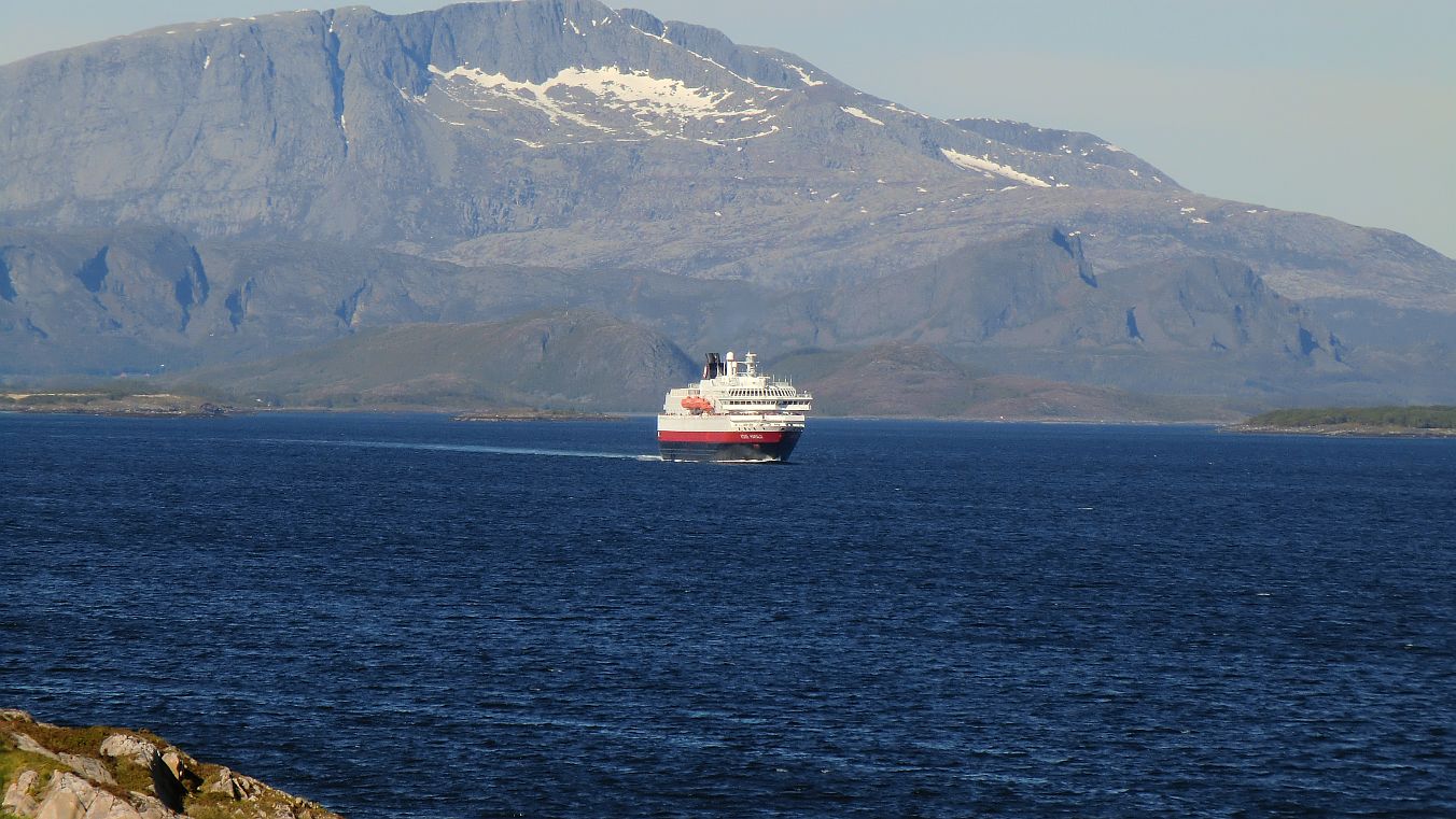 Im Gimsefjord kommt das südwärts fahrende Hurtigrutenschiff von Brønnøsund gegen 17:30 Uhr am Torghatten vorbei